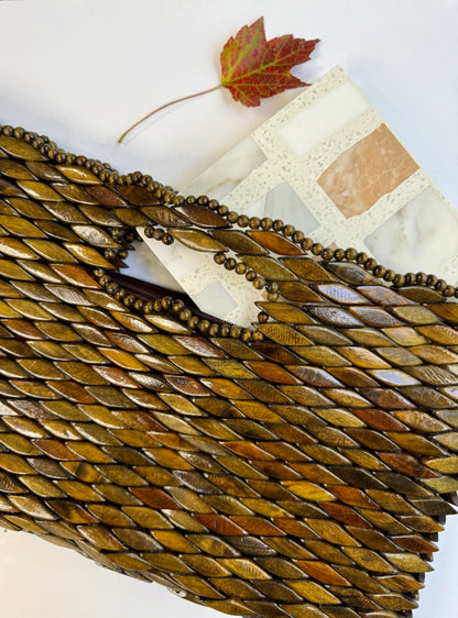 A Carlo Scarpa - Mountain High tile by New York Cement Tile, a beaded brown clutch, and a red maple leaf on white.