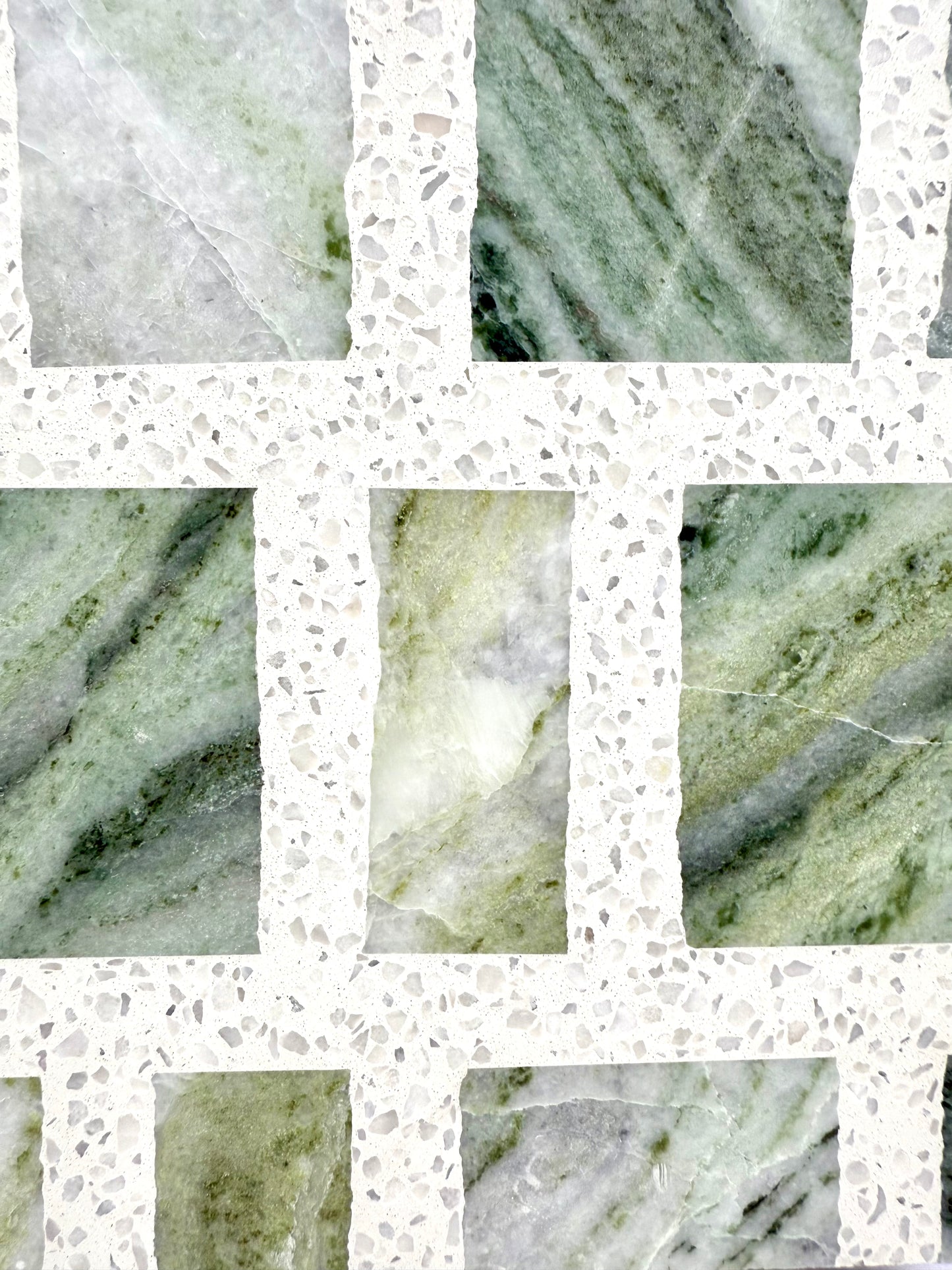 Close-up of Carlo Scarpa - Green Vibes by New York Cement Tile: wavy green tiles, divided by speckled terrazzo strips.