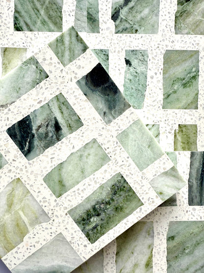 Two Carlo Scarpa - Green Vibes tiles by New York Cement Tile overlap on a white terrazzo background.