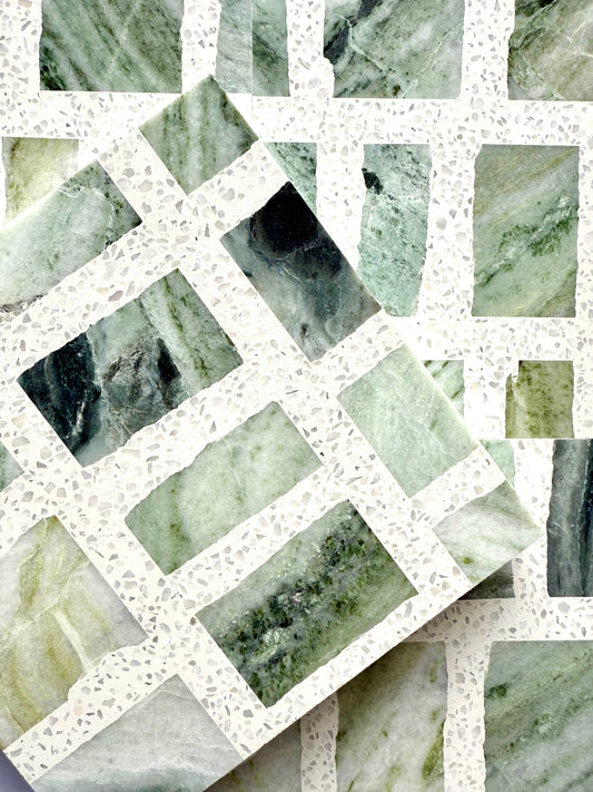Two Carlo Scarpa - Green Vibes tiles by New York Cement Tile overlap on a white terrazzo background.