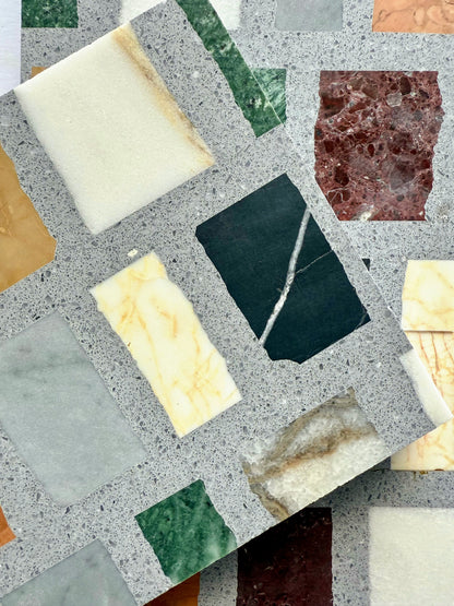 Two Carlo Scarpa-Multicolor Dark tiles by New York Cement Tile overlap, showing multicolor marble in a light gray matrix.