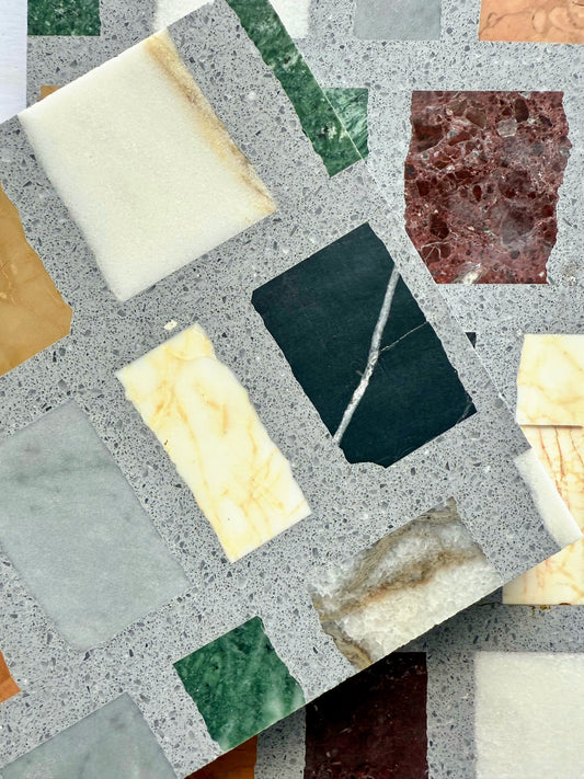 Two Carlo Scarpa-Multicolor Dark tiles by New York Cement Tile overlap, showing multicolor marble in a light gray matrix.