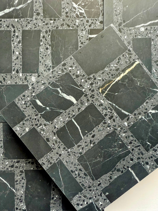 Carlo Scarpa- Black by New York Cement Tile: black and gray grid-patterned tile with white veining, one stacked diagonally.