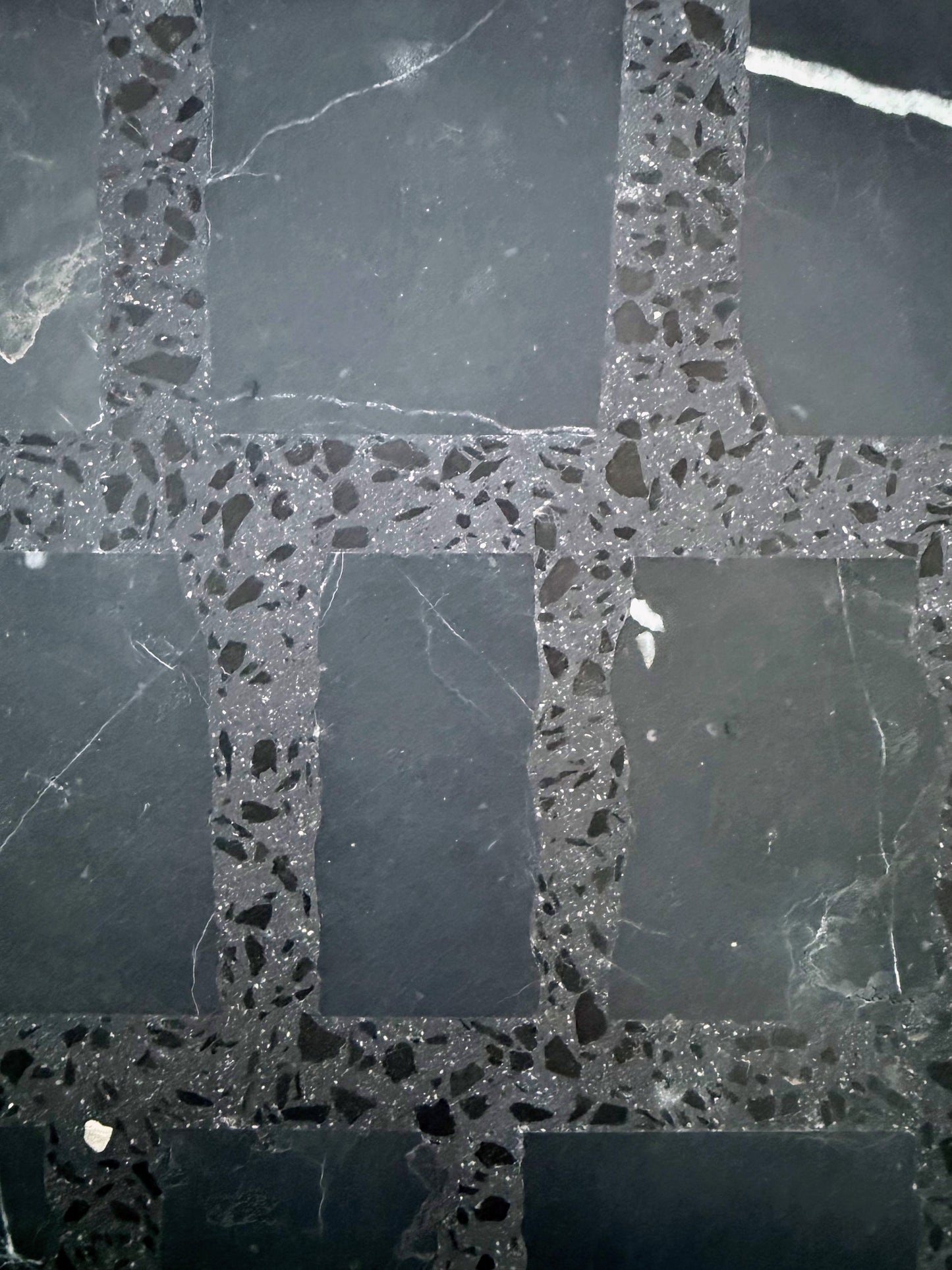 Carlo Scarpa-Black tiles by New York Cement Tile feature smooth, dark grey stone with speckled grout in a grid pattern.