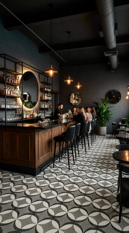 A modern bar with Petalos Pebble Terrazzo floors by New York Cement Tile, dark walls, pendant lights, and bar stools.