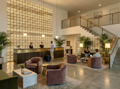 Modern hotel lobby with velvet chairs, plants, and a Large Tonga breeze block wall by New York Cement Tile.