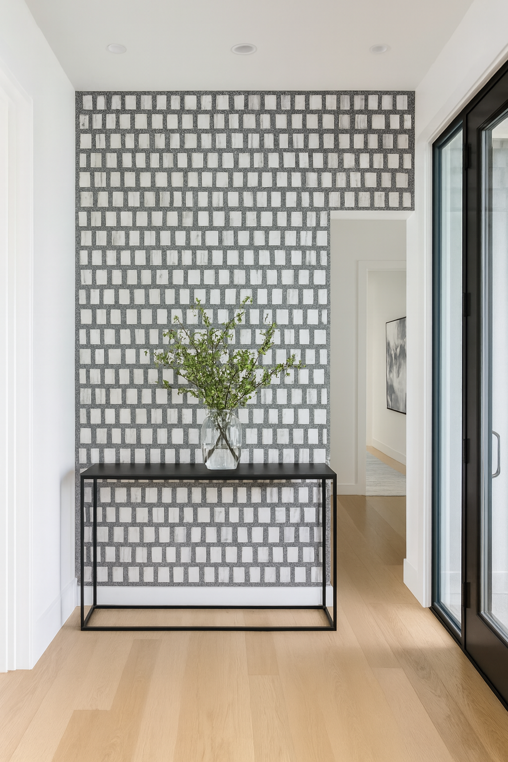 A modern hallway features Carlo Scarpa-Dark Gray tiles by New York Cement Tile, a black console, and a vase with green branches.