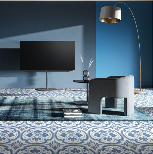 Modern living room with N20-569 Blue cement tiles by New York Cement Tile, blue walls, gray chair, and wall-mounted TV.