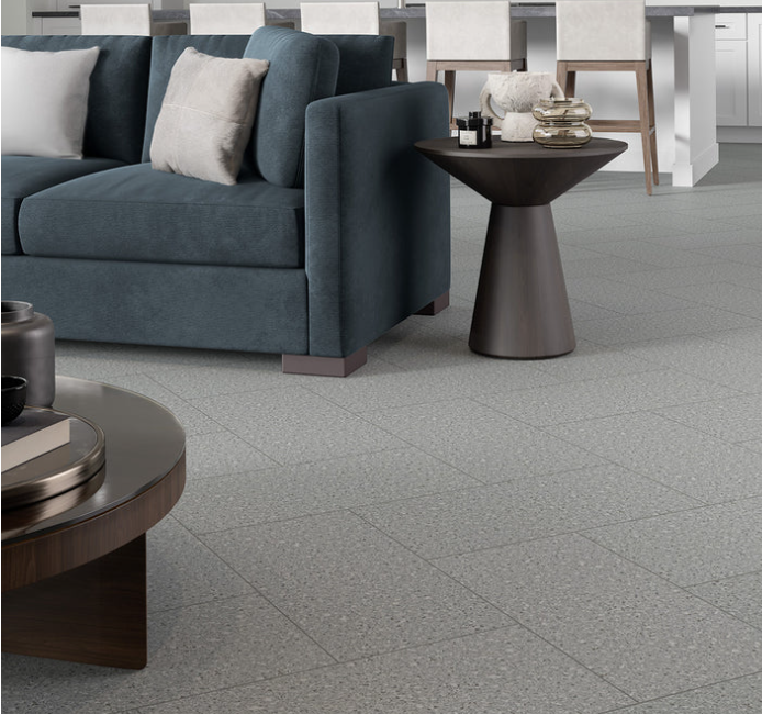 Modern living room with blue sofa, coffee tables, and New York Cement Tile FRAGMENTO-SILVER SMALL SPECKLE near kitchen.