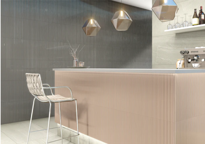 Modern kitchen with a beige textured island, metal chair, pendant lights, and shelves with bottles and glasses.