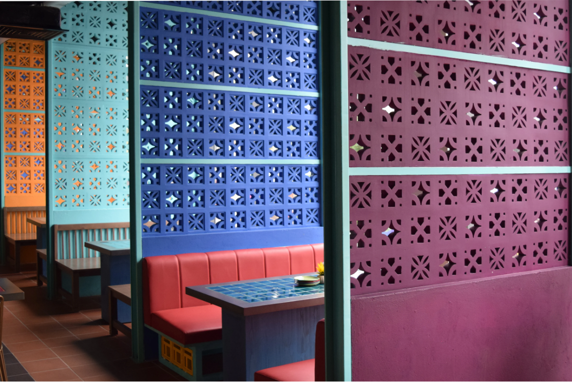 Colorful restaurant booths divided by patterned blue, purple, and orange walls with geometric cutout designs.