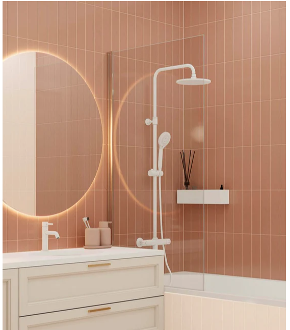 Modern bathroom with peach tiles, white vanity, round backlit mirror, and a white shower set with a shelf and reed diffuser.