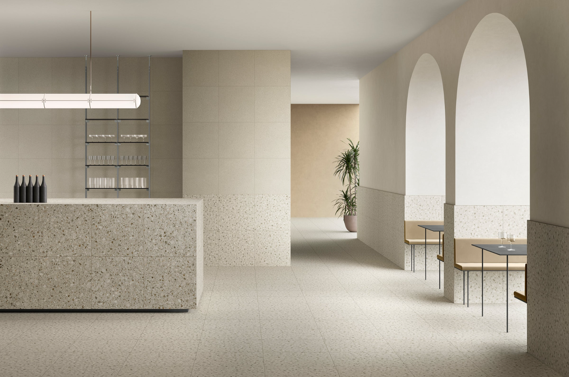 Minimalist cafe interior with terrazzo surfaces, arched wall openings, small tables, and a potted plant in the background.