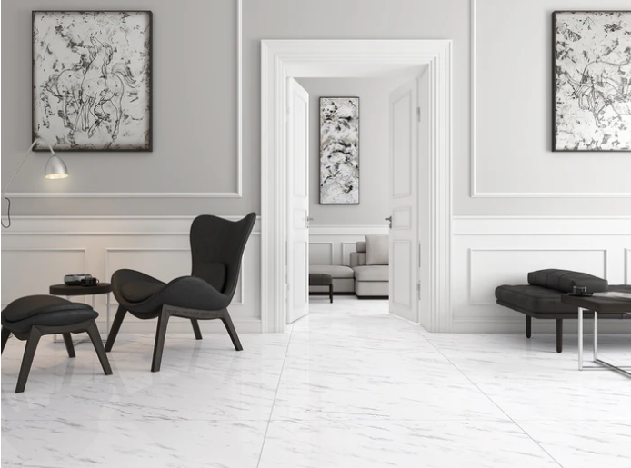 Modern living room with black lounge chairs, white marble floor, abstract art, and an open doorway to another stylish room.