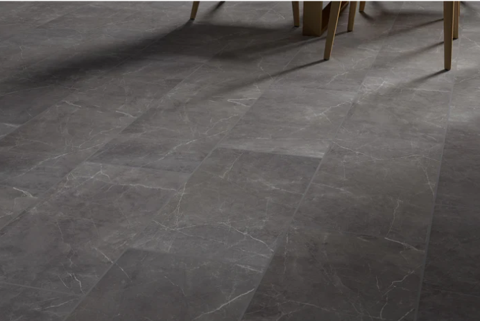 Gray stone tile floor with subtle white veining, partially shadowed by wooden chair legs.