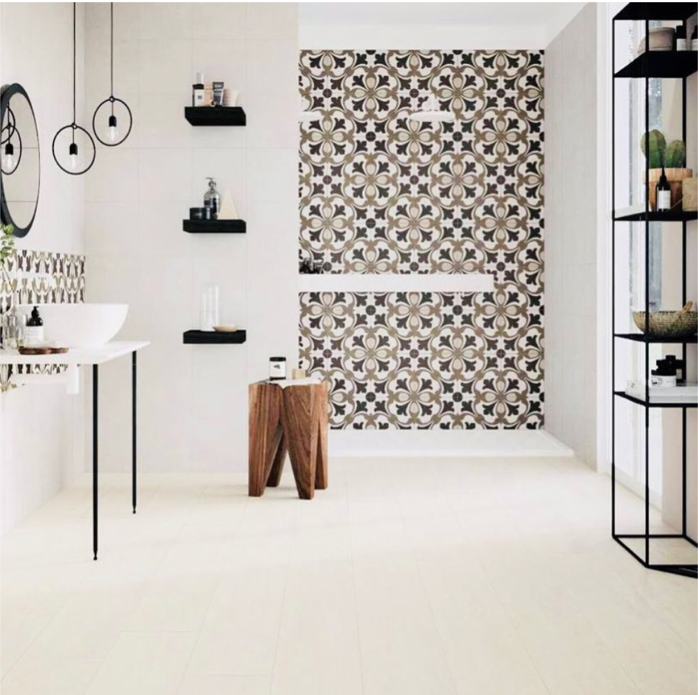 Modern bathroom with patterned tile accent wall, black shelves, a round mirror, and a white sink on slim black legs.