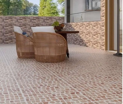 Outdoor patio with Carlo Scarpa- Earth tiles by New York Cement Tile; wicker chairs, table, stone wall, and greenery.