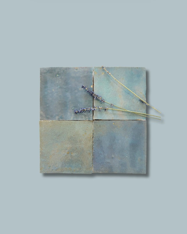 Four Deep Teal tiles by New York Cement Tile in a grid, accented with three lavender sprigs placed diagonally on top.