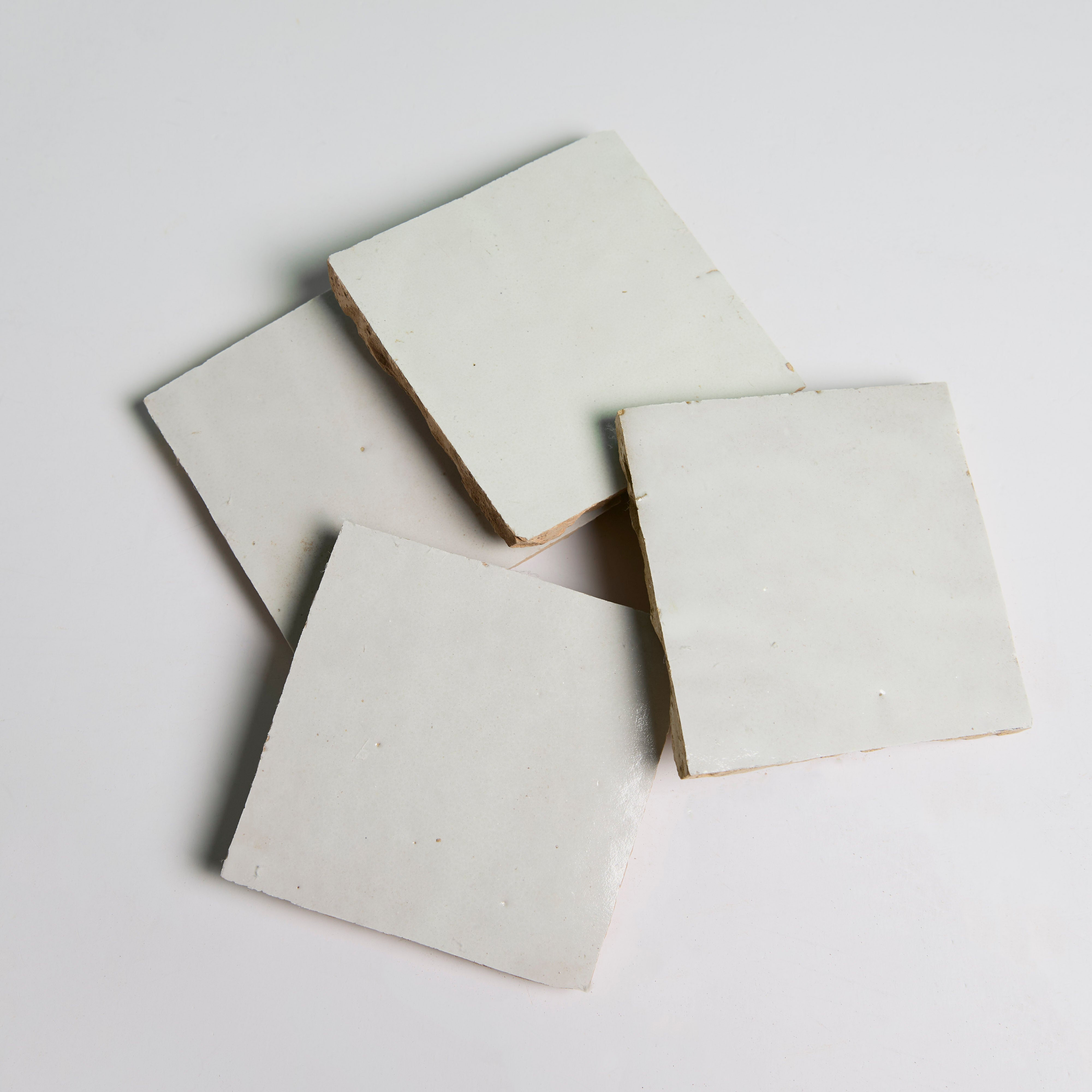 Four Ivory Cloud tiles by New York Cement Tile are arranged in an overlapping pattern on a plain white background.