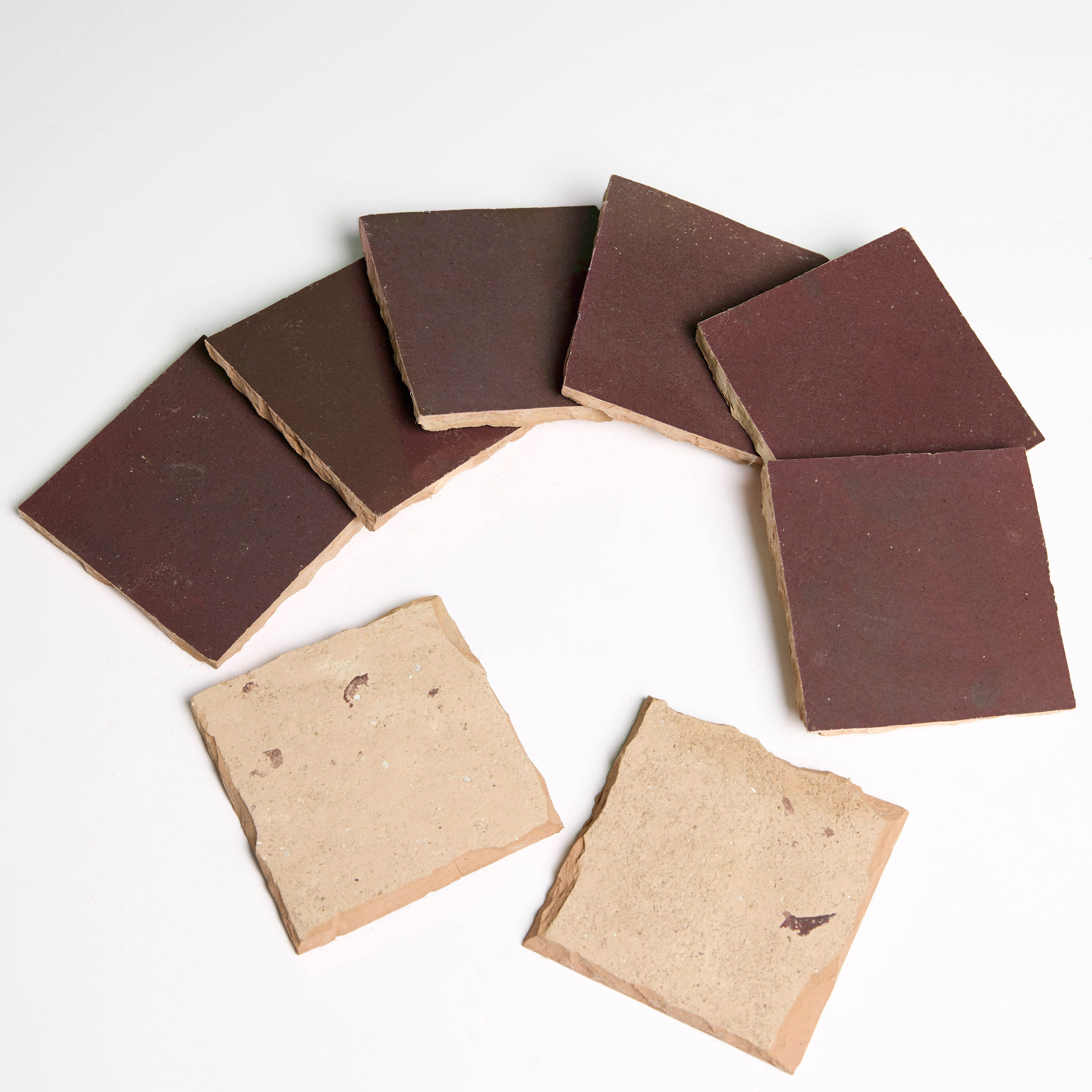 Six Thistle tiles by New York Cement Tile form a reddish-brown arc, with two tiles below on a white background.