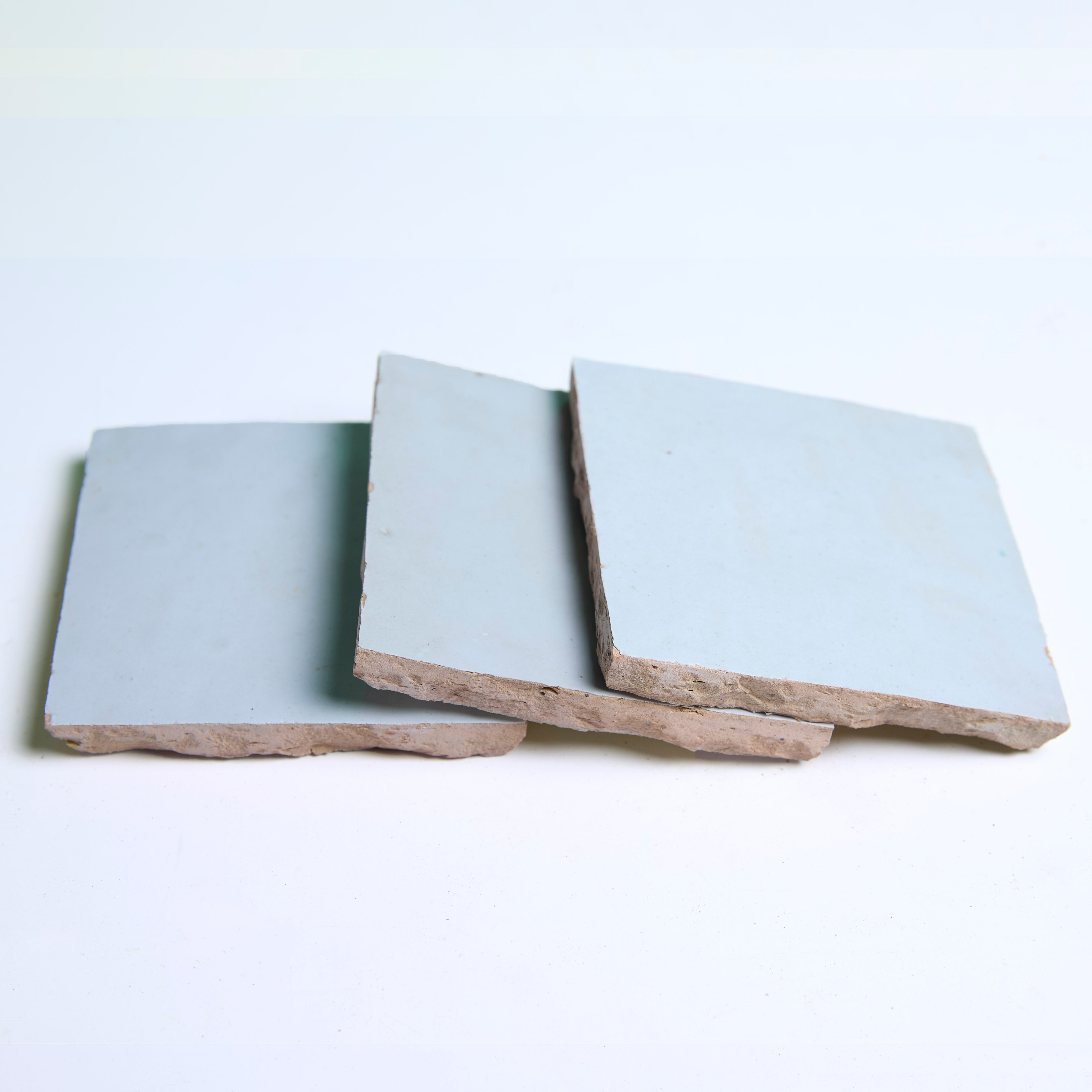 Three Magical Blue tiles by New York Cement Tile are stacked unevenly on a white surface.