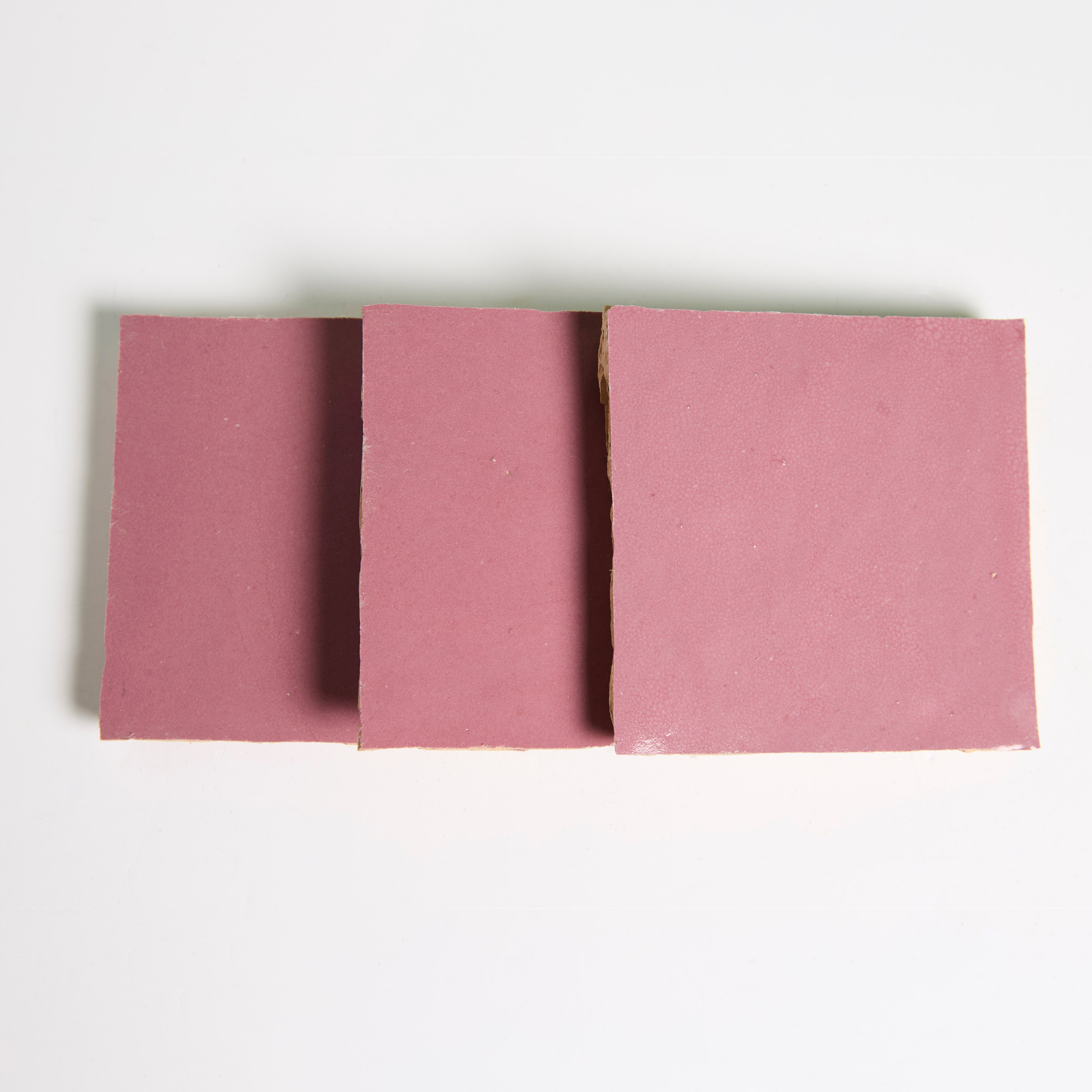 Three square Vintage Rose desserts by New York Cement Tile, pink and smooth, slightly overlapping on a white background.