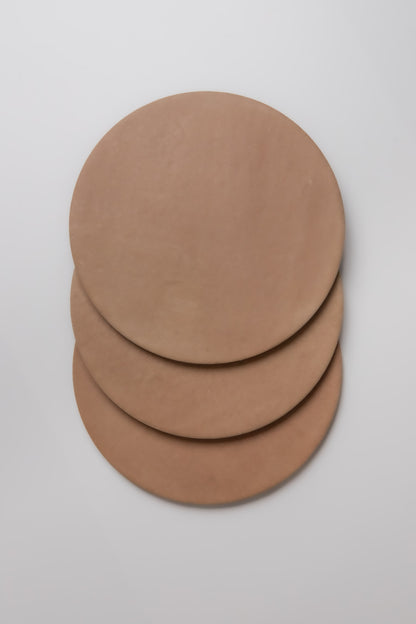 Three round Finca Arcilla samples are stacked on a white surface.