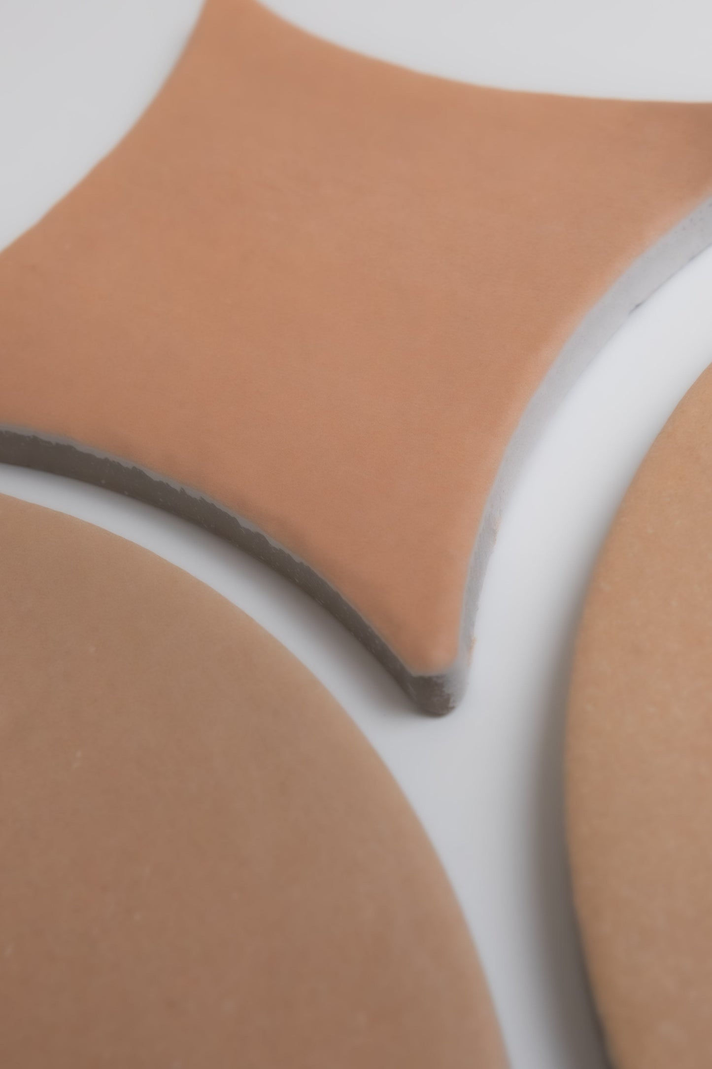Three Finca Arcilla tile samples in geometric shapes, including a rounded square and circles, on a white background.