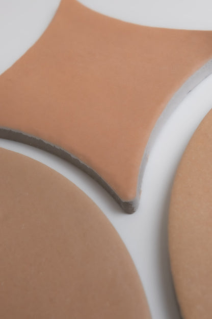 Three Finca Arcilla tile samples in geometric shapes, including a rounded square and circles, on a white background.