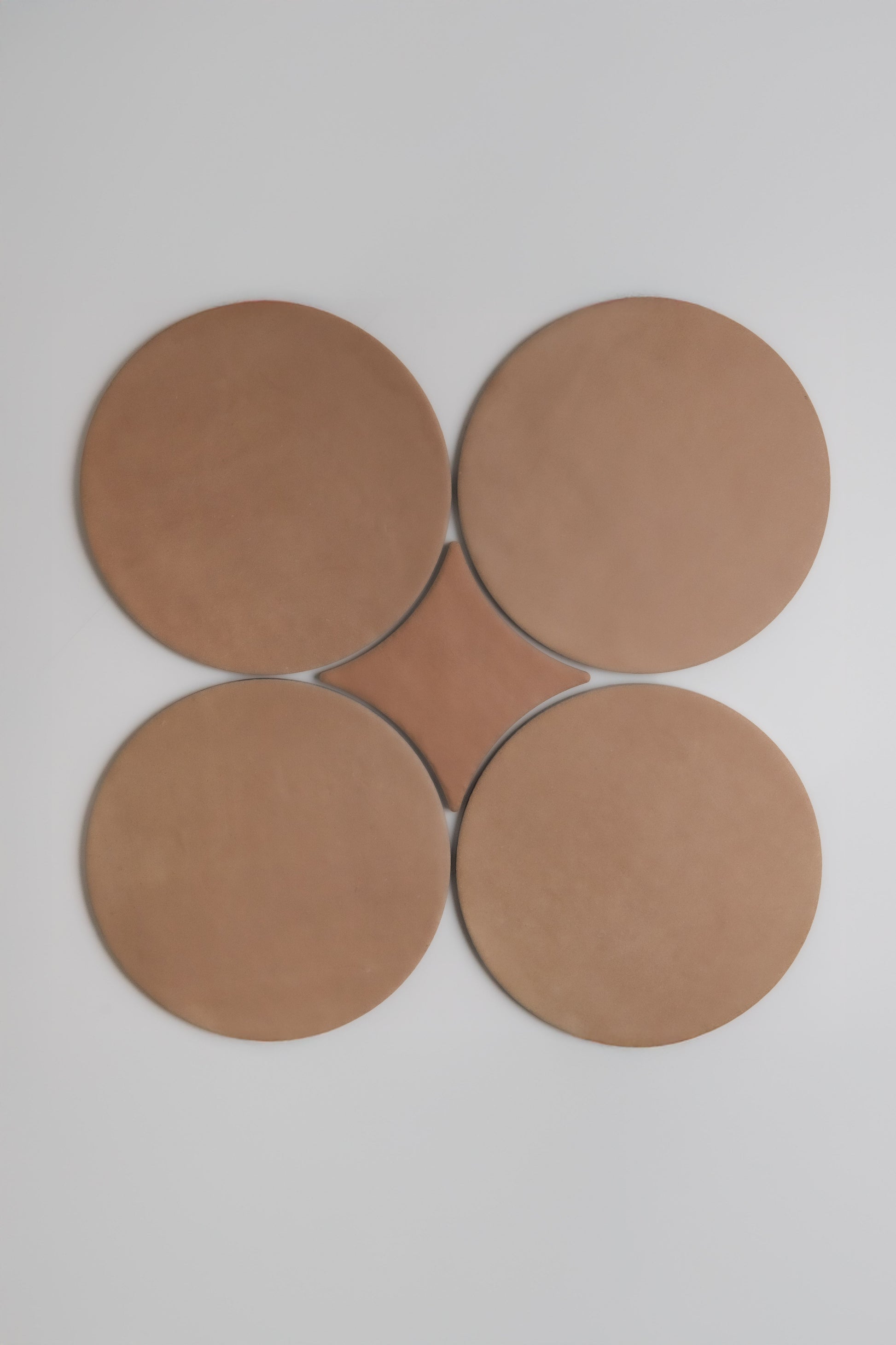 Four large brown circles from Finca's Arcilla Sample form a clover-like pattern on a white background.