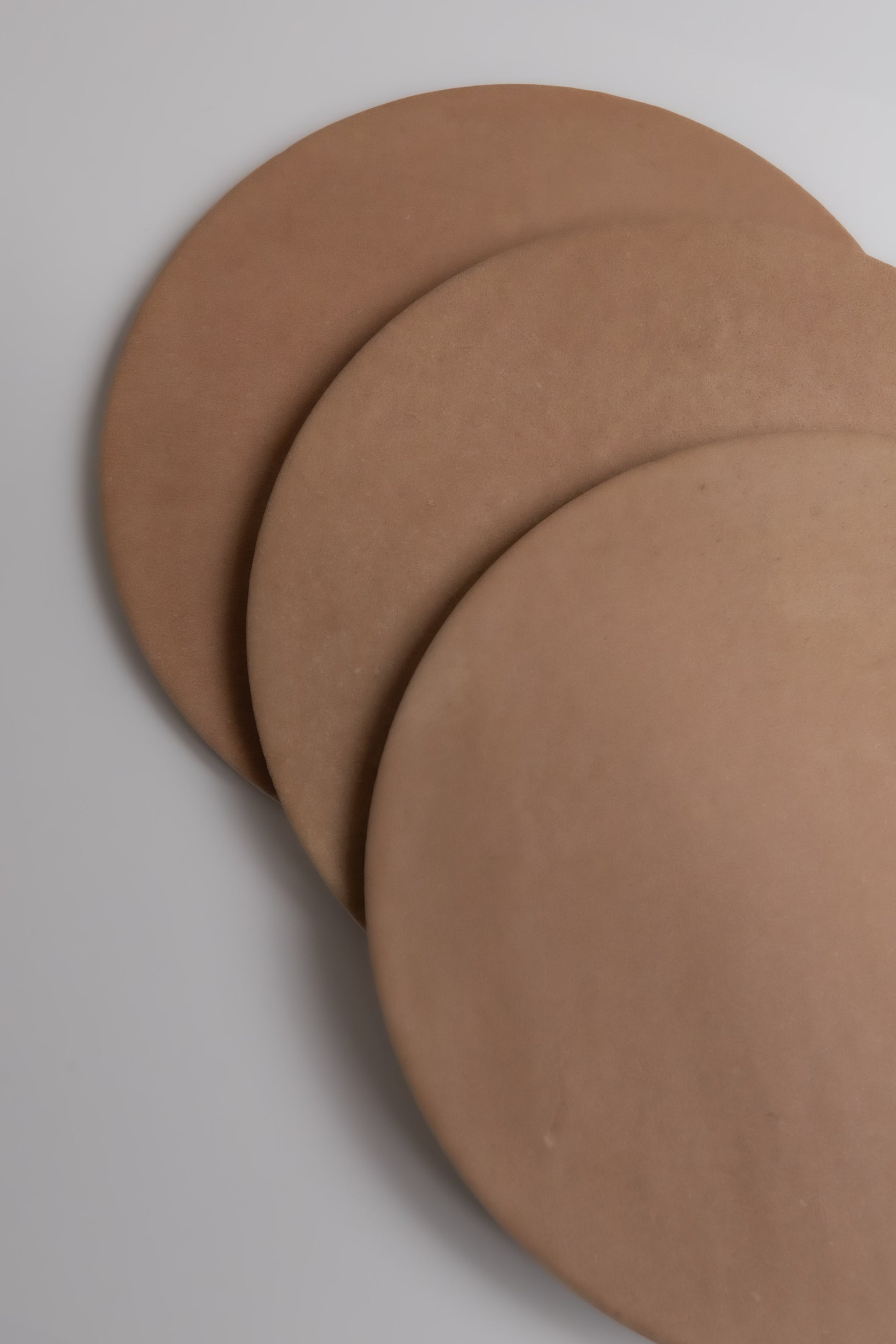 Three overlapping Arcilla samples by Finca in brown shades, arranged diagonally on a light surface.