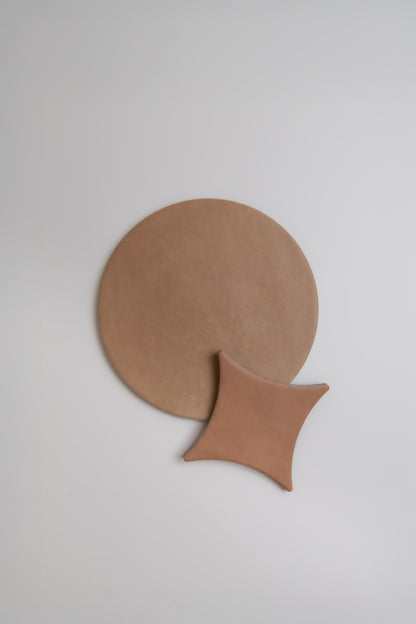 The Finca Arcilla Sample shows a large round tan mat and a smaller square tan mat overlapping on a white background.
