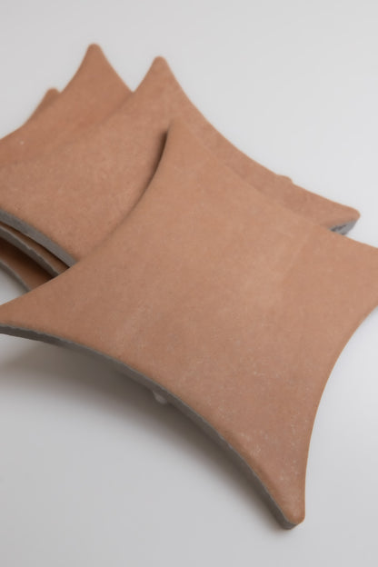 Three Arcilla tile samples by Finca with curved edges stacked on a white surface, viewed from above.