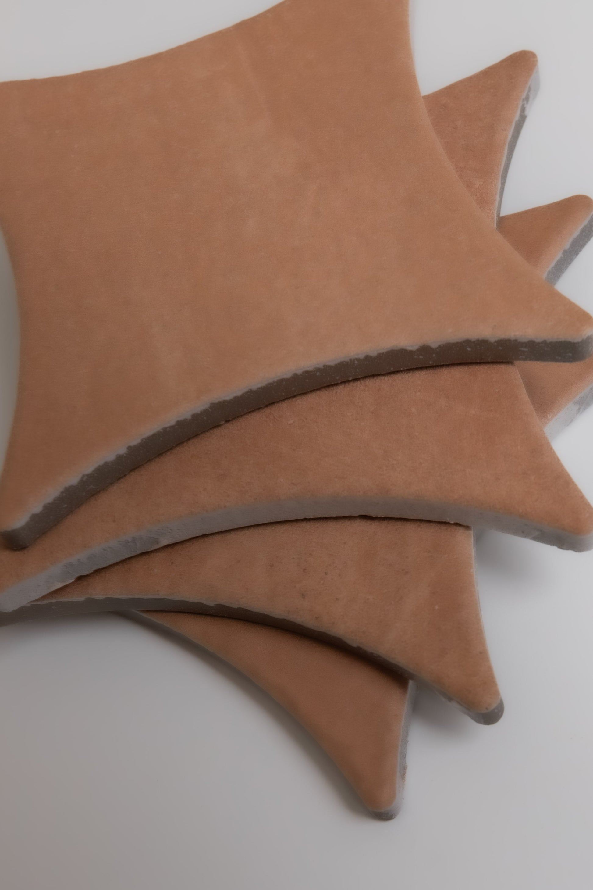 Three overlapping, star-shaped Arcilla tiles by Finca with pointed edges are displayed on a white background.