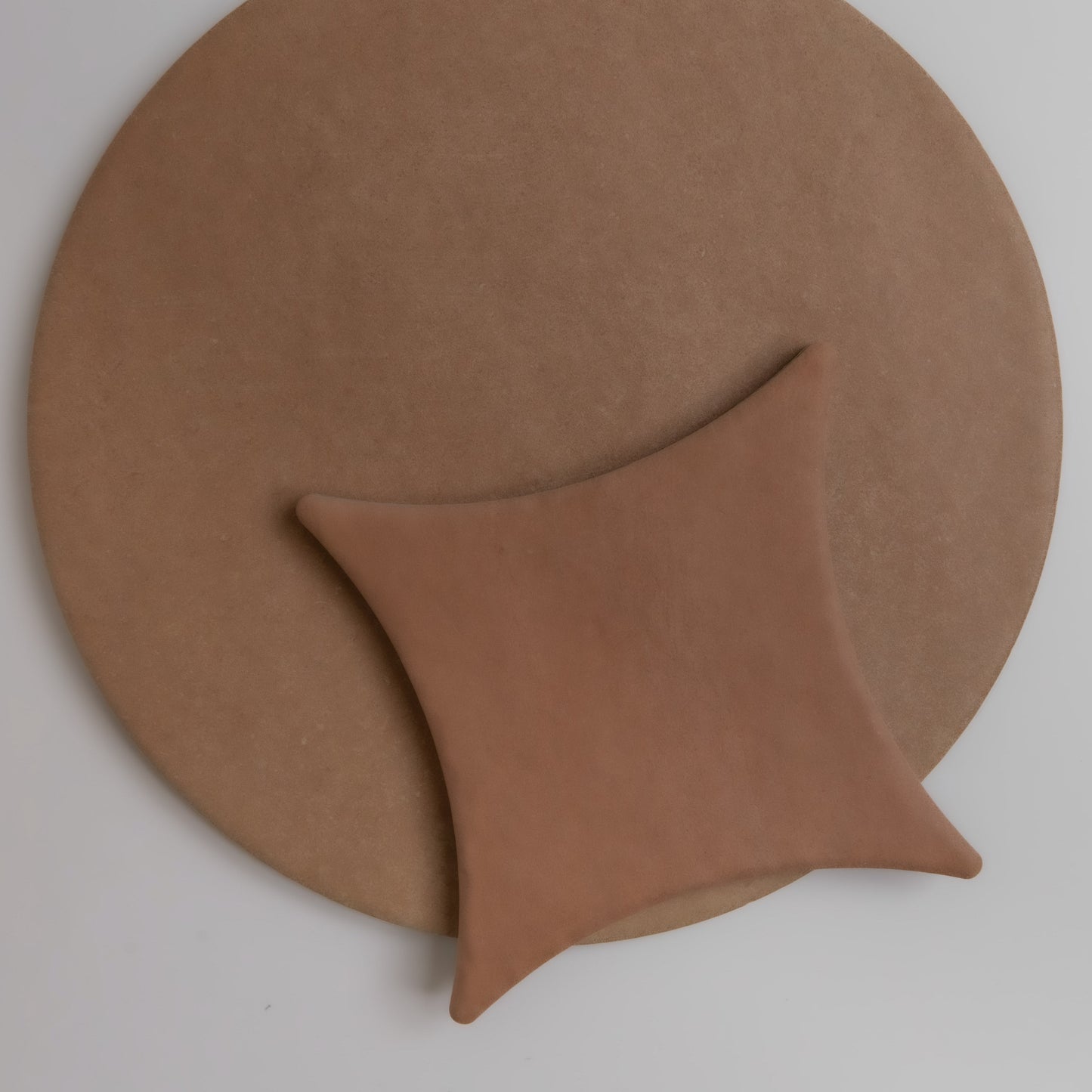 The Finca Arcilla, Sample features a round brown mat with a soft, star-shaped cushion placed off-center on top.