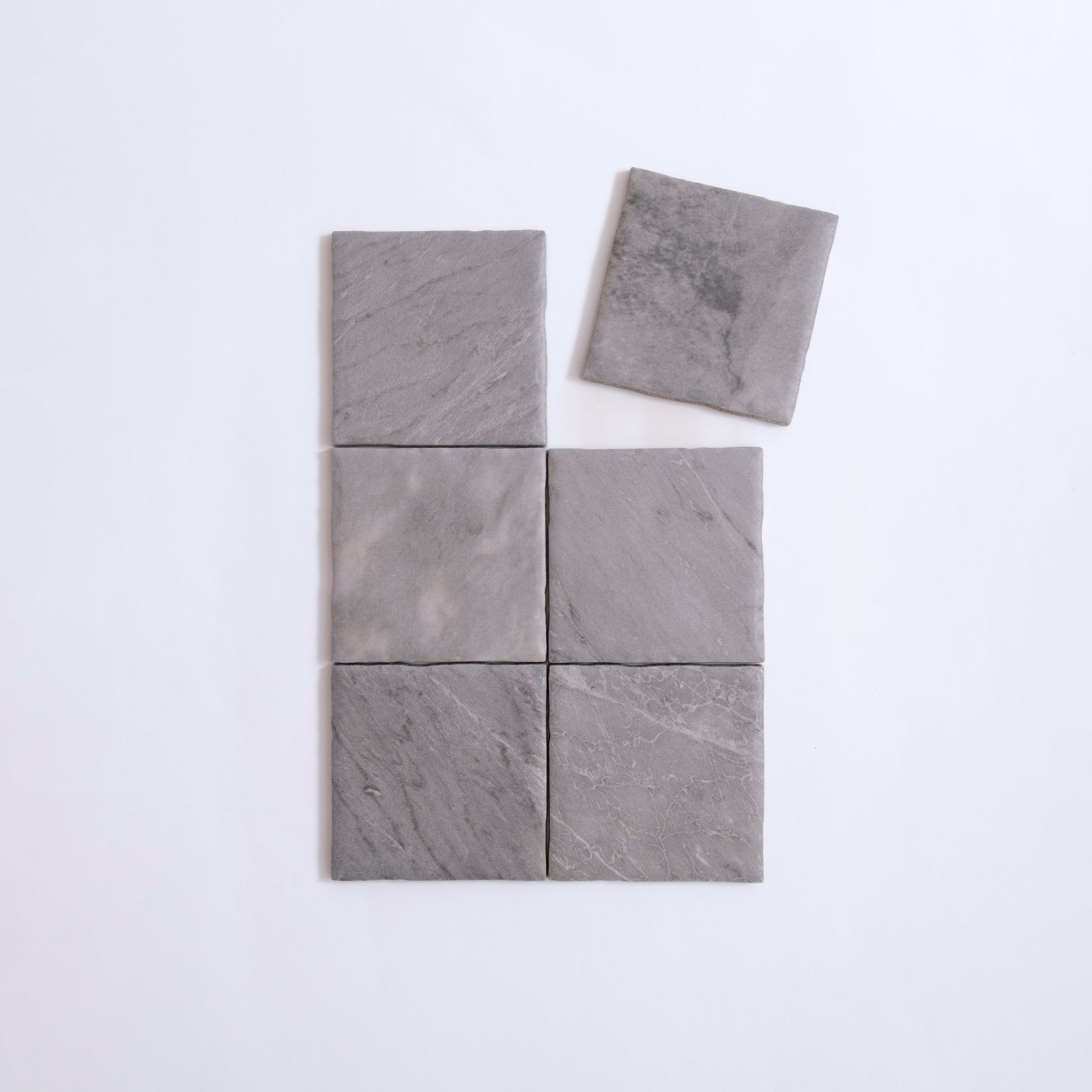 Six Bardiglio sample tiles by Tosca in gray stone, grid-arranged with top right tile offset on white background.
