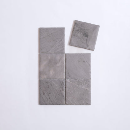 Six Bardiglio sample tiles by Tosca in gray stone, grid-arranged with top right tile offset on white background.