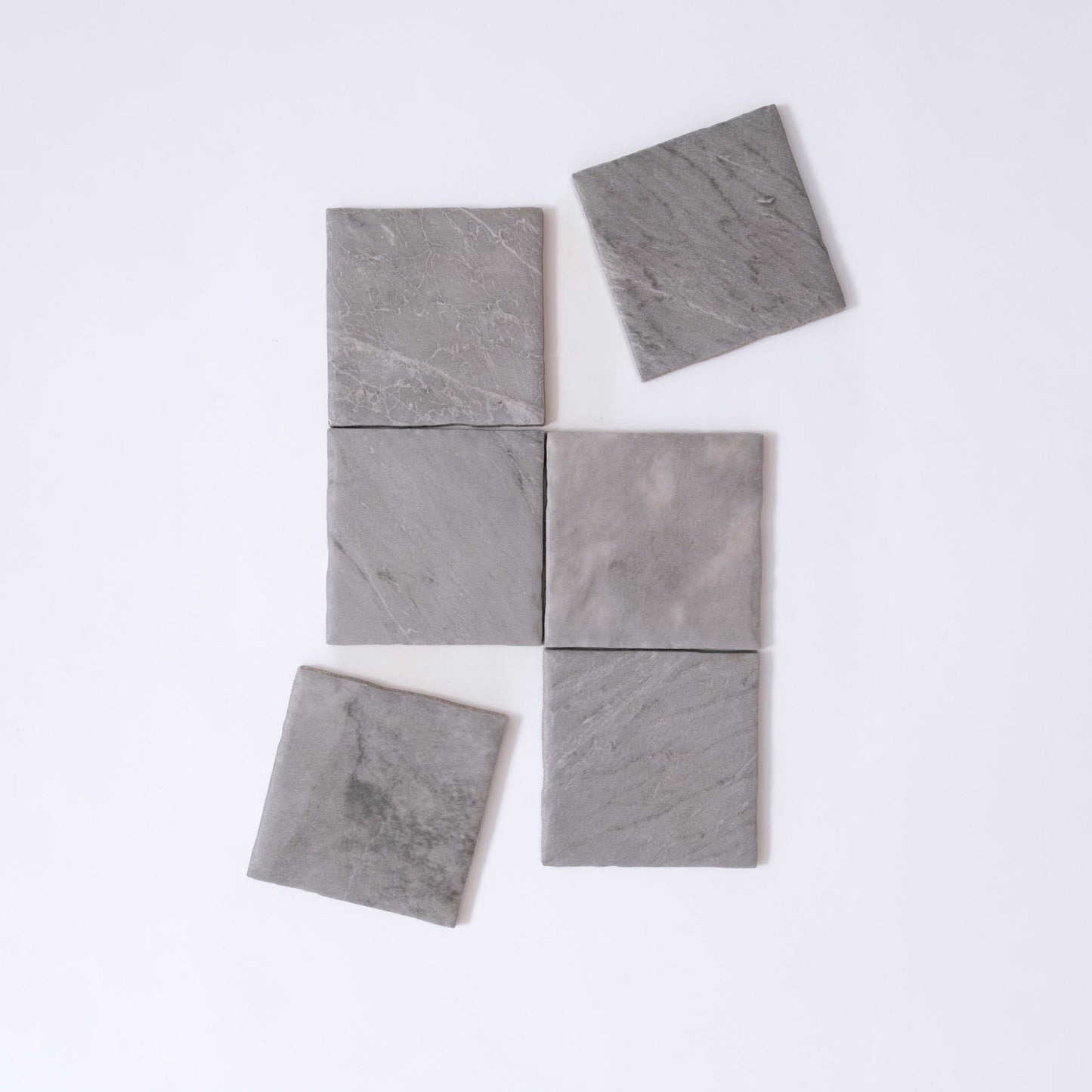 Six Tosca Bardiglio sample tiles, gray stone, arranged unevenly on white; two tiles are slightly misaligned.