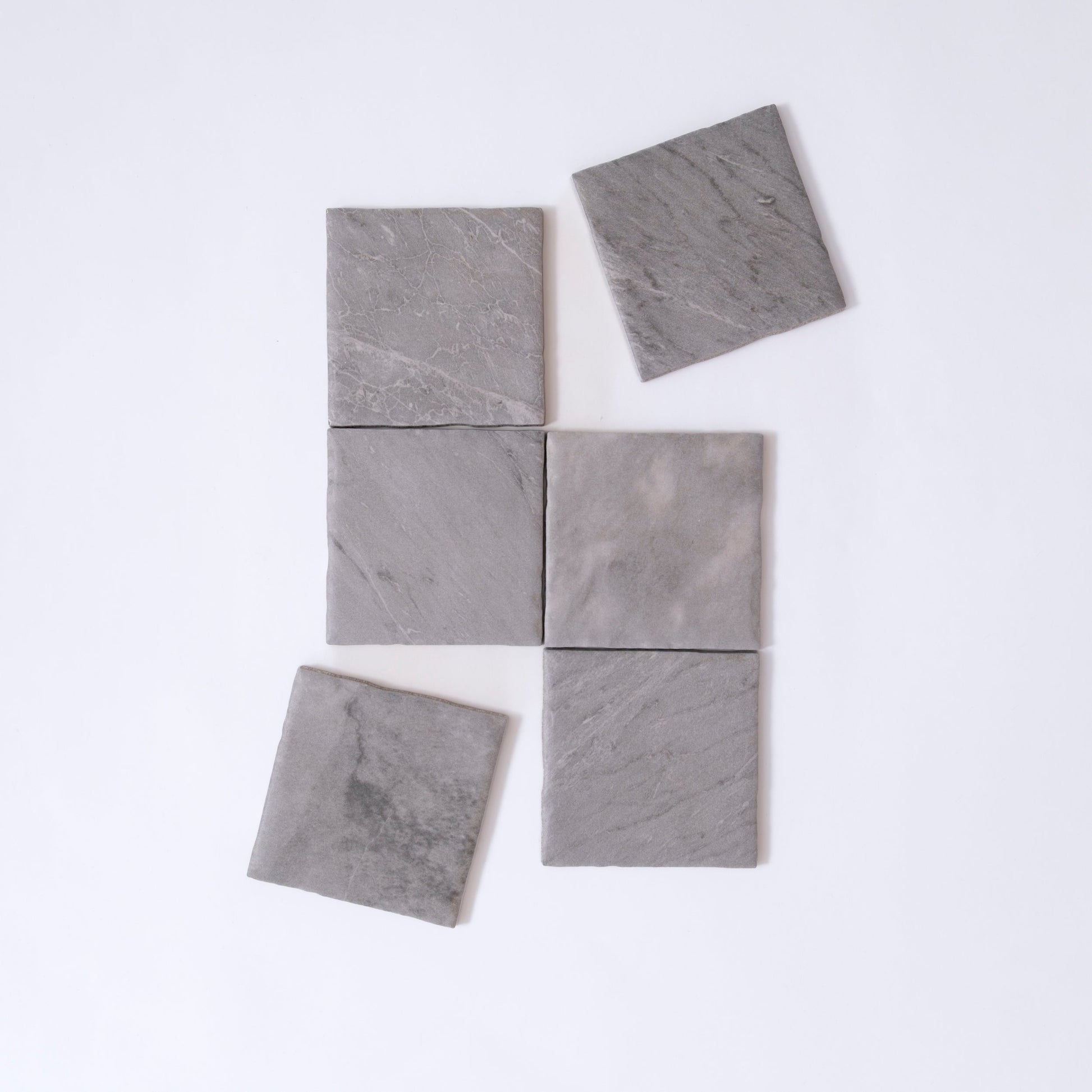 Six Tosca Bardiglio sample tiles, gray stone, arranged unevenly on white; two tiles are slightly misaligned.