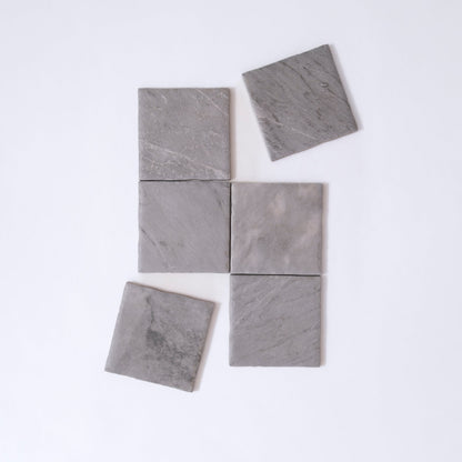 Six Tosca Bardiglio sample tiles, gray stone, arranged unevenly on white; two tiles are slightly misaligned.