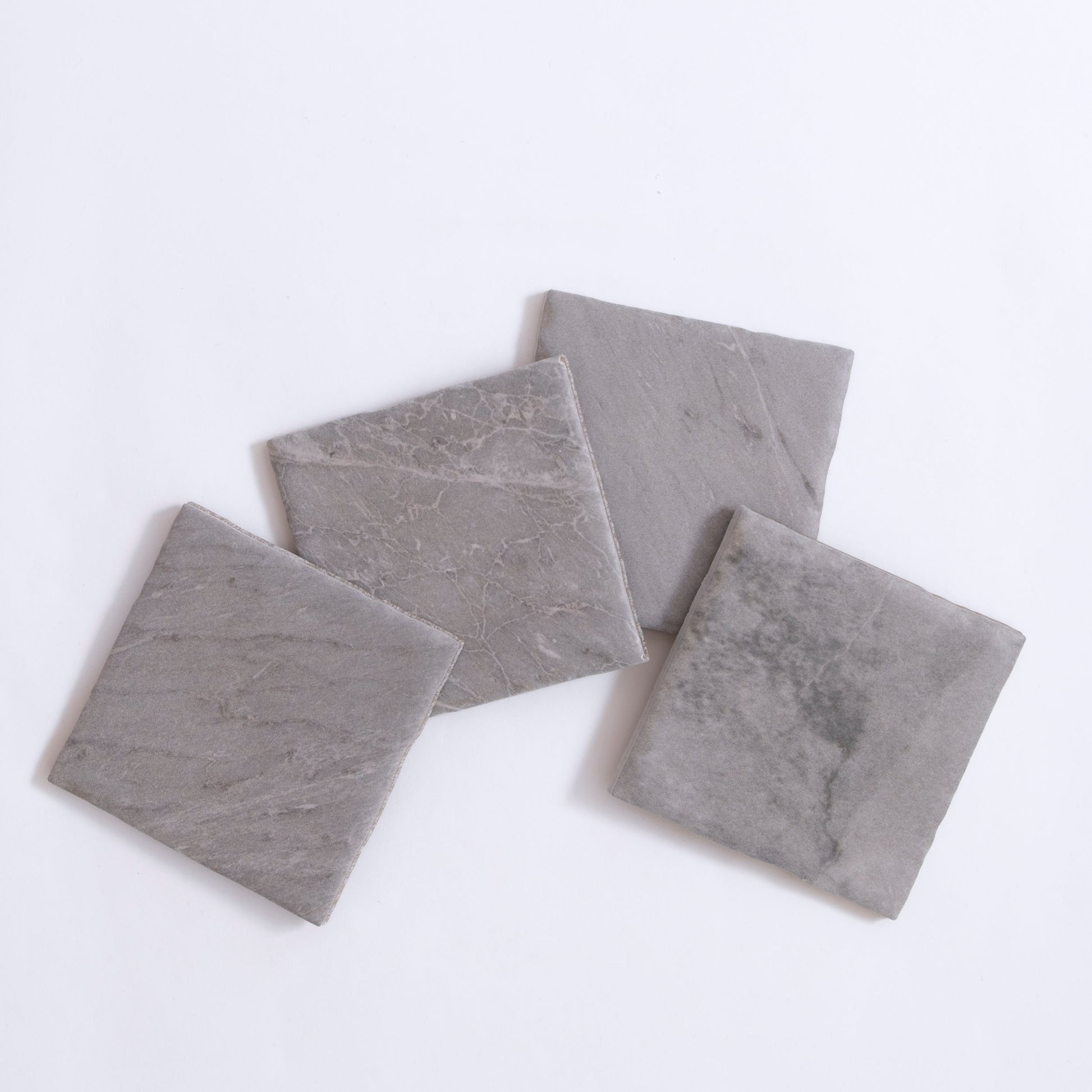 Four Bardiglio gray stone tile samples by Tosca, arranged in overlapping squares on a white background.