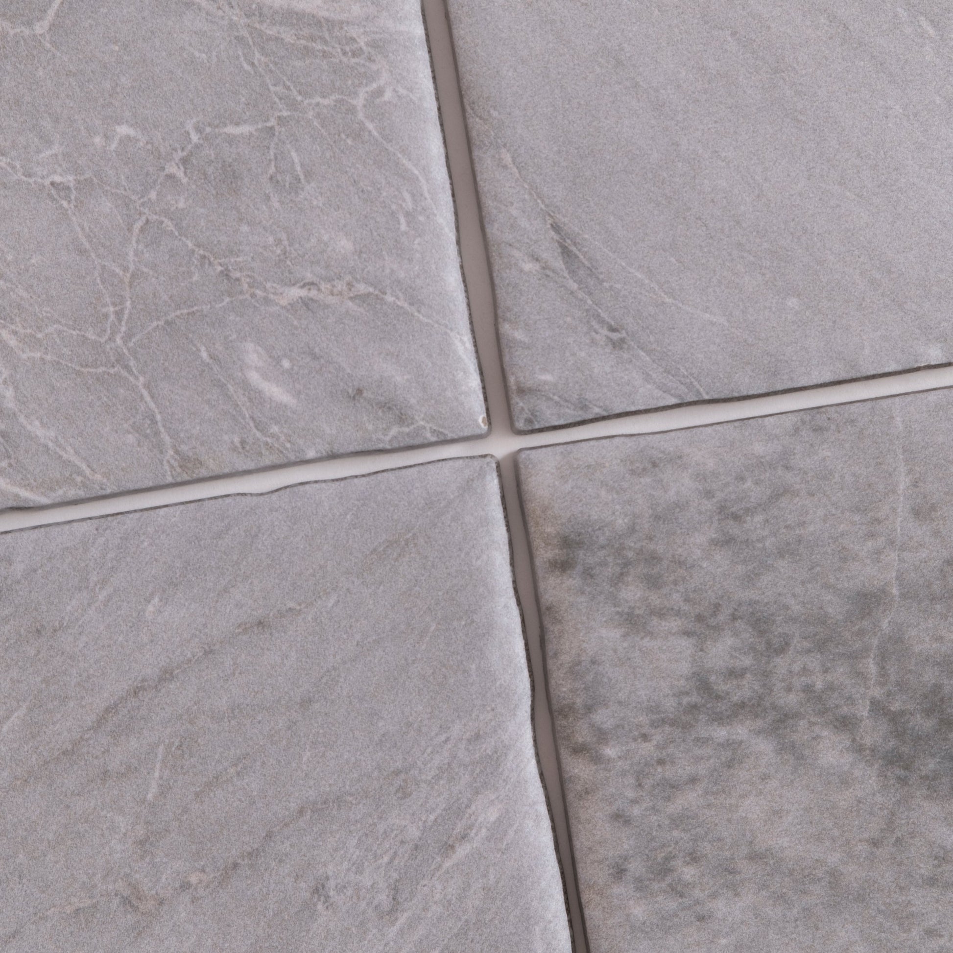 Four Bardiglio Sample tiles by Tosca in gray, with varied textures and white veining, separated by thin grout lines.