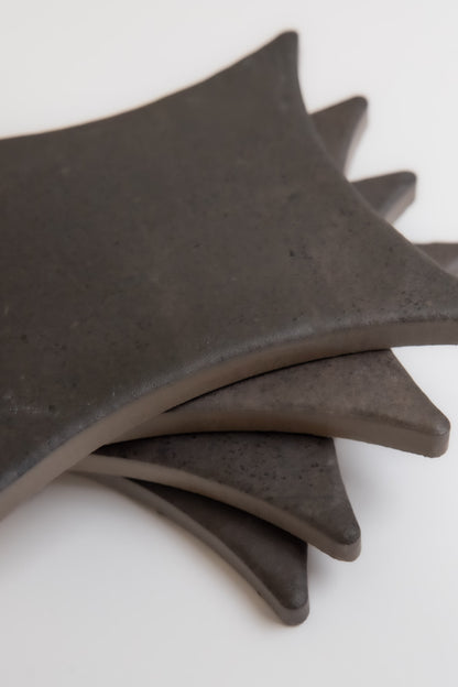 Four Finca Black Horse, Extra Sample ceramic coasters, dark and square with rounded edges, fanned on a white background.