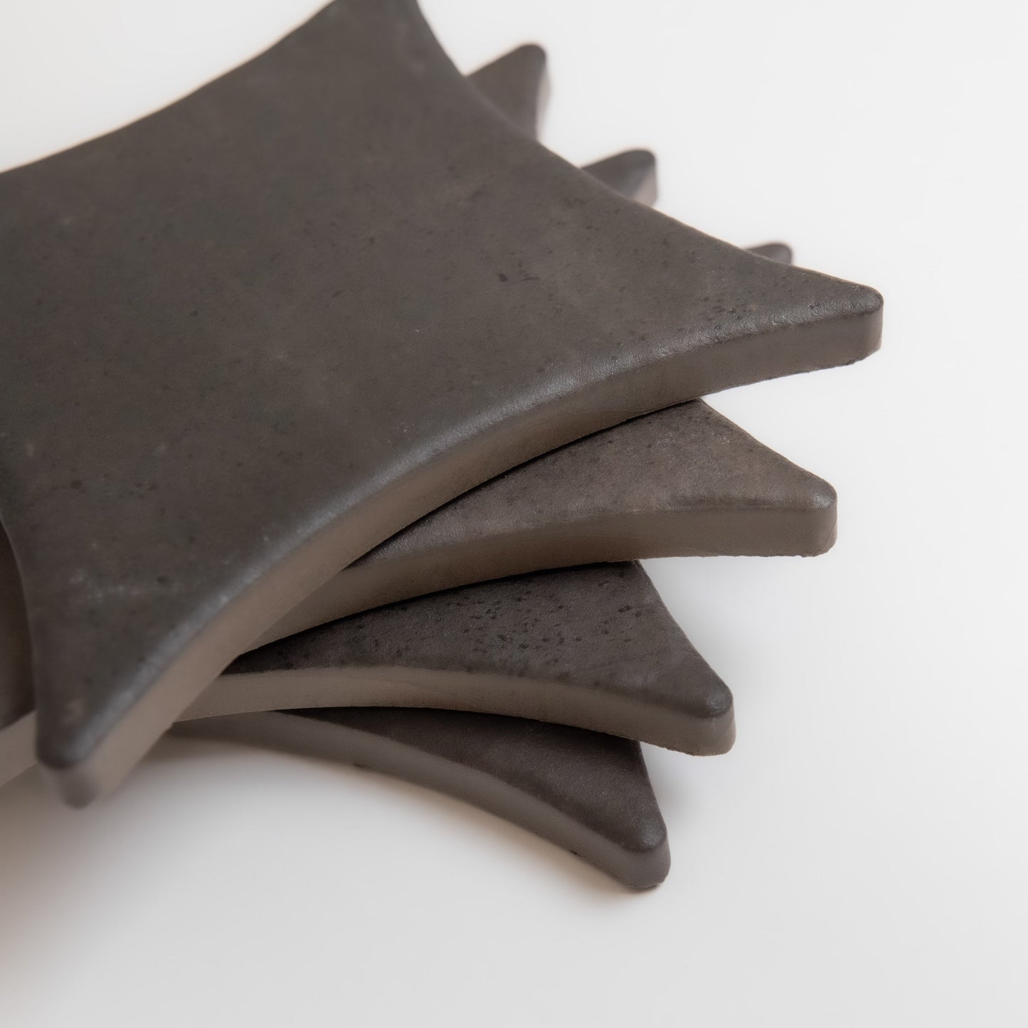 Four Finca Black Horse Extra Sample coasters are stacked on a white surface, slightly fanned out.