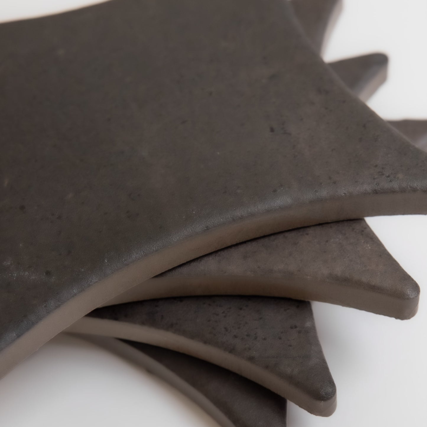 Four Black Horse sample tiles by Finca, dark and square with curved edges, arranged fanned on a white background.