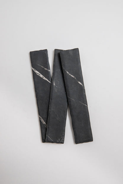 Two Tosca Black Marble, Extra Sample slabs with white veins form a loose "N" on a light gray background.