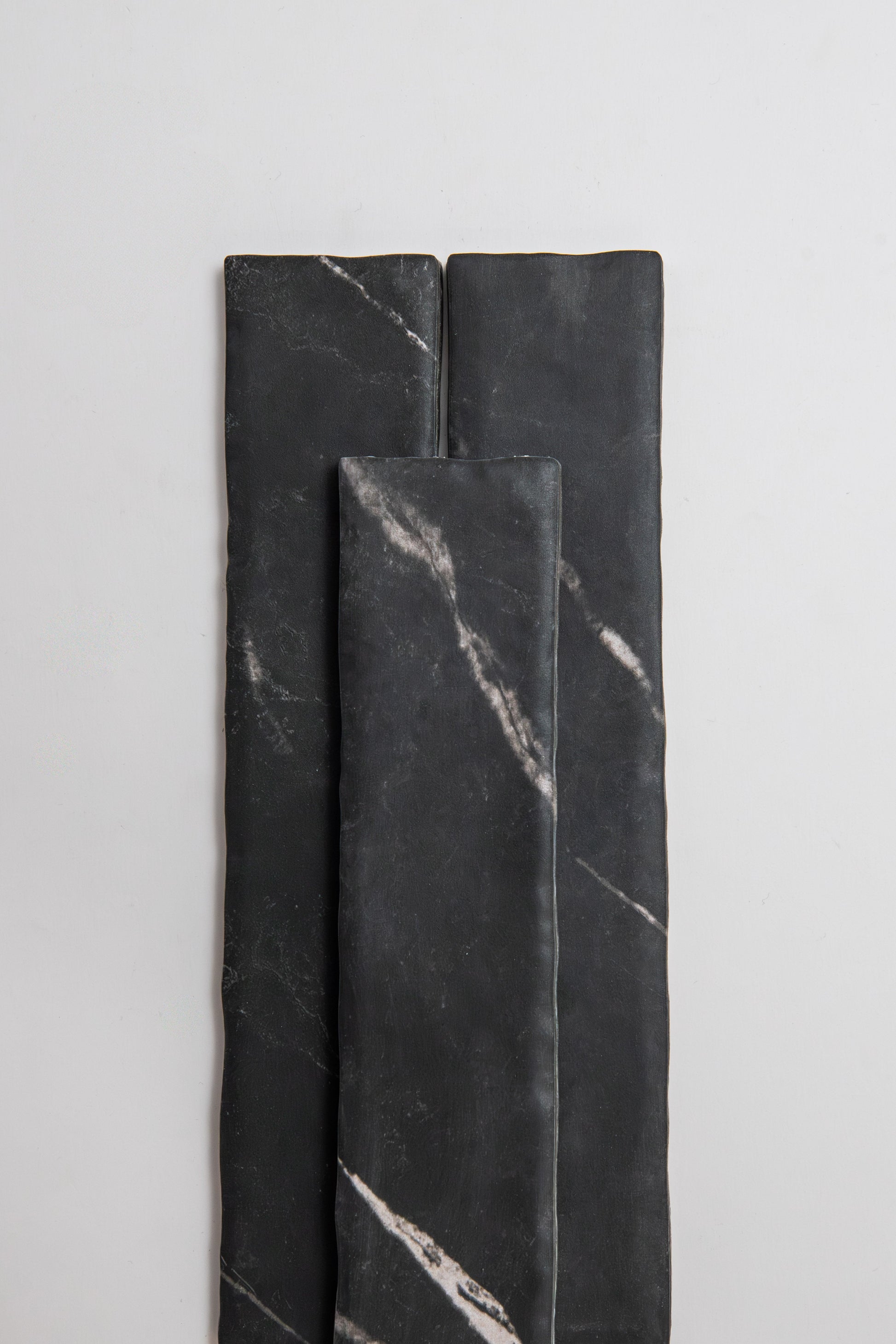 Three Tosca 'Black Marble, Extra Sample' tiles with white veining, arranged vertically on a light background.