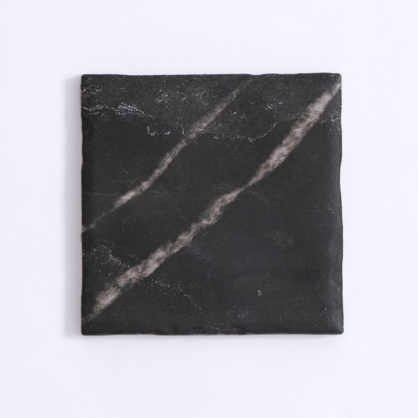 The Tosca Black Marble, Extra Sample is a square black tile with faint white streaks and a slightly uneven surface.
