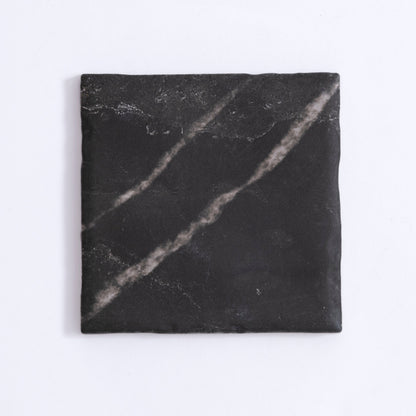 The Tosca Black Marble, Extra Sample is a square black tile with faint white streaks and a slightly uneven surface.