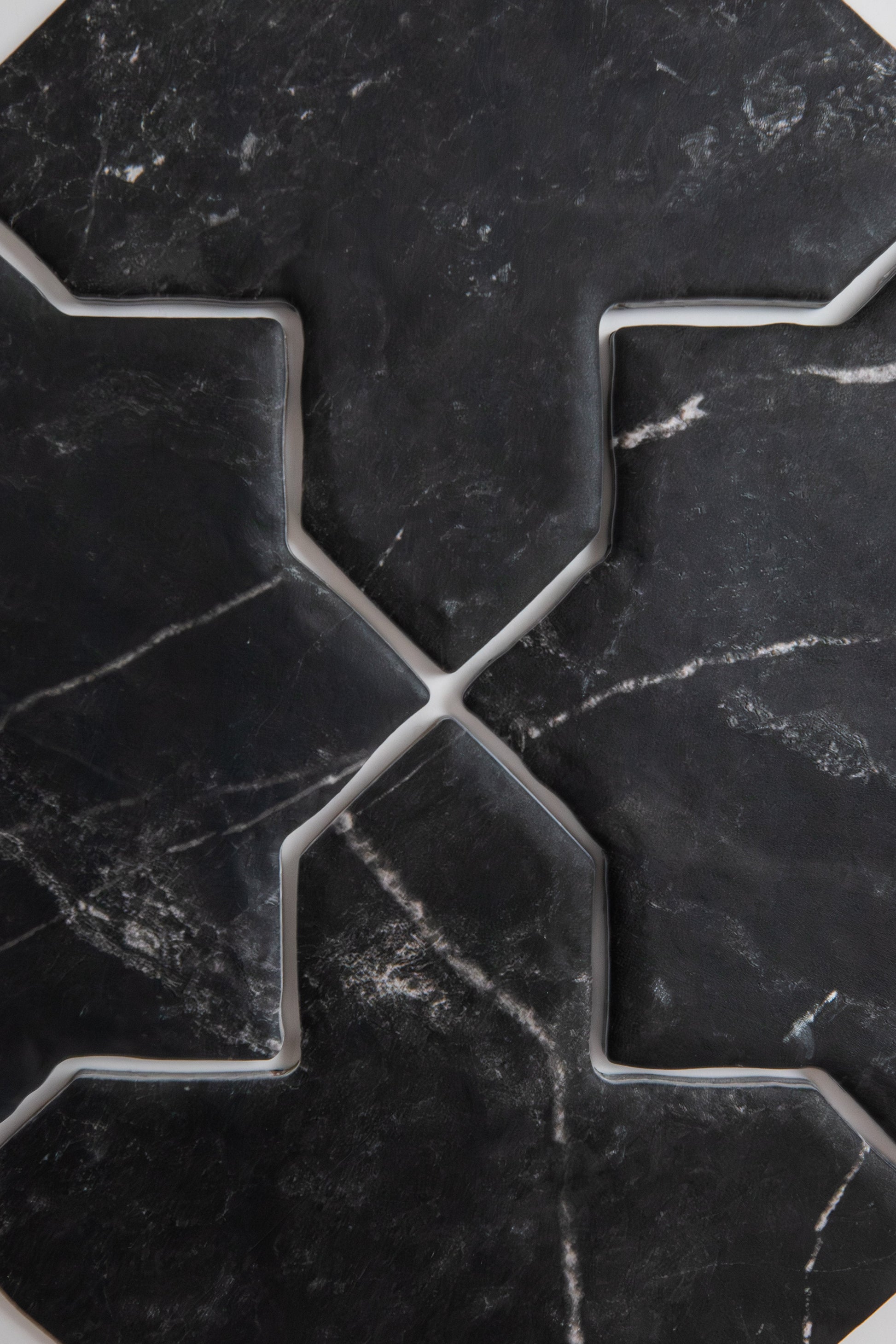 A close-up of Tosca's Black Marble, Extra Sample tiles with white veining in a geometric, symmetric pattern.